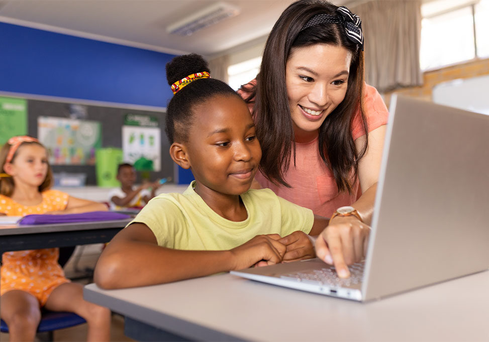 Teacher helping a student on her computer.
